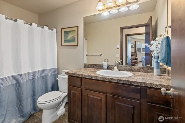 a bathroom with a granite countertop toilet sink and mirror