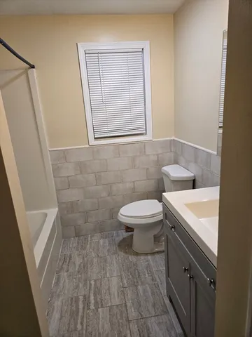 a bathroom with a sink a toilet a window and vanity