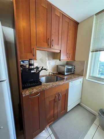a kitchen with stainless steel appliances granite countertop a sink a stove a refrigerator a washer and dryer