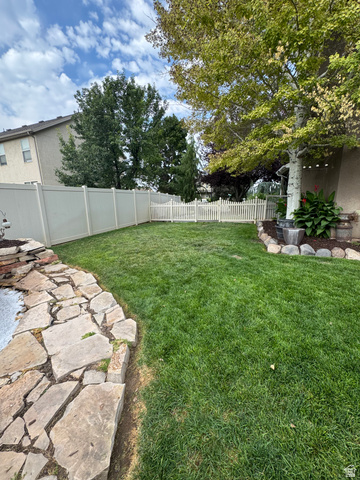 1237 South 260 West Payson, UT 84651 - Photo 12 of 81 Expansive backyard featuring a lush lawn, a stone-edged garden bed, mature trees, and a combination of privacy and picket fencing