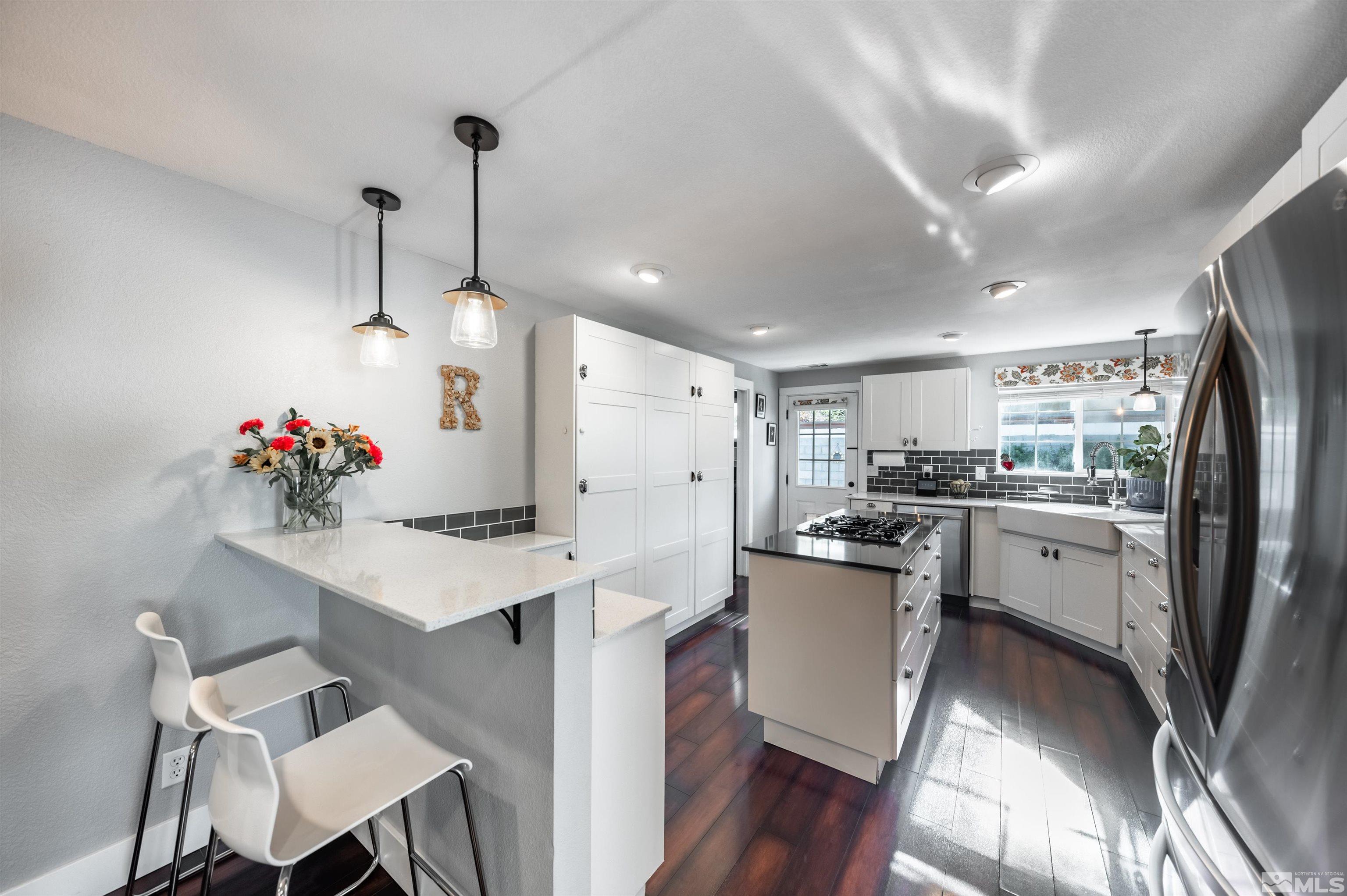 3901 Warren Way Reno, NV 89509 - Photo 14 of 40 a kitchen with stainless steel appliances granite countertop a refrigerator a sink dishwasher a dining table and chairs with wooden floor