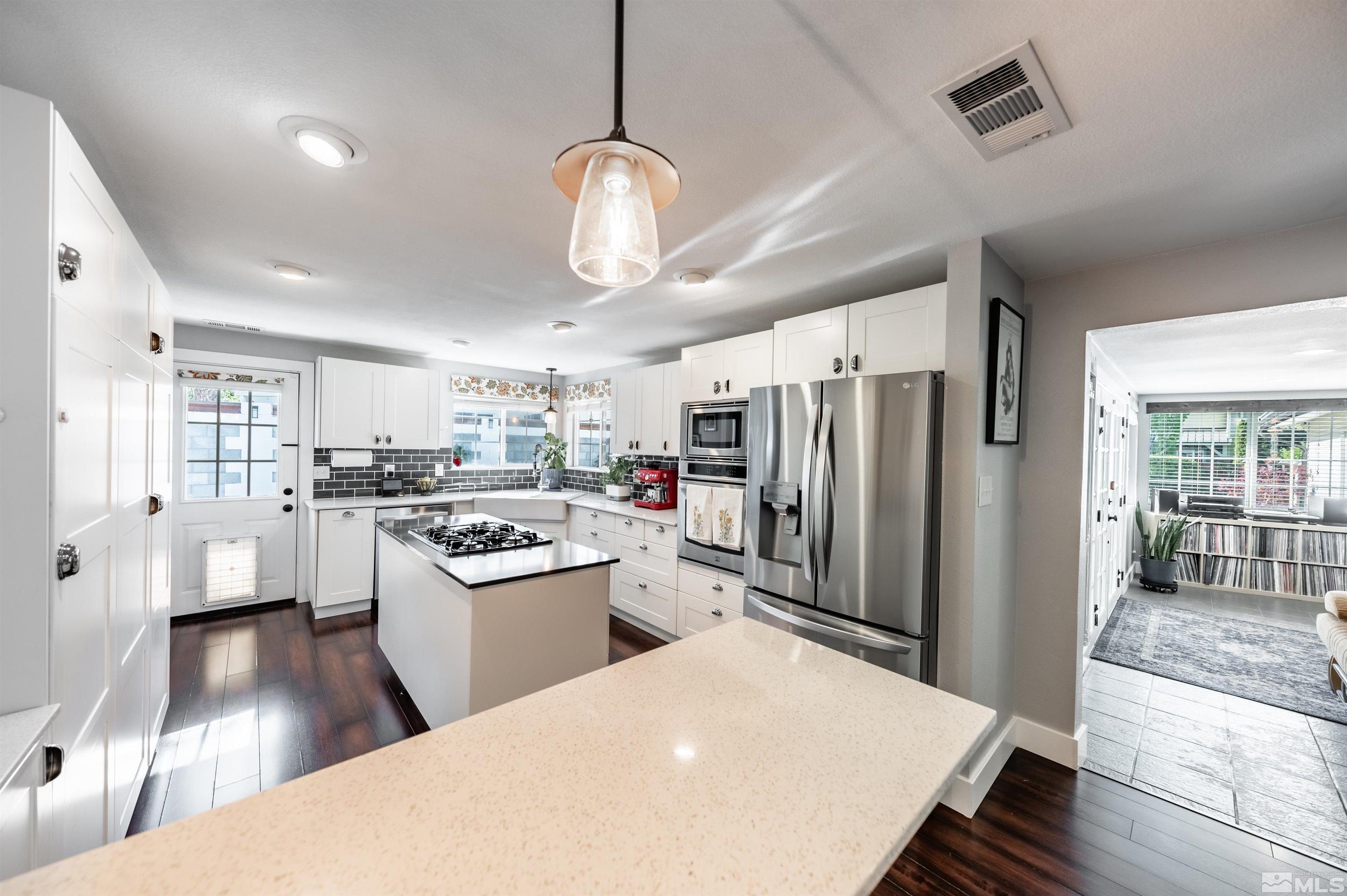 3901 Warren Way Reno, NV 89509 - Photo 16 of 40 a kitchen with a refrigerator a sink dishwasher a stove and white cabinets with wooden floor