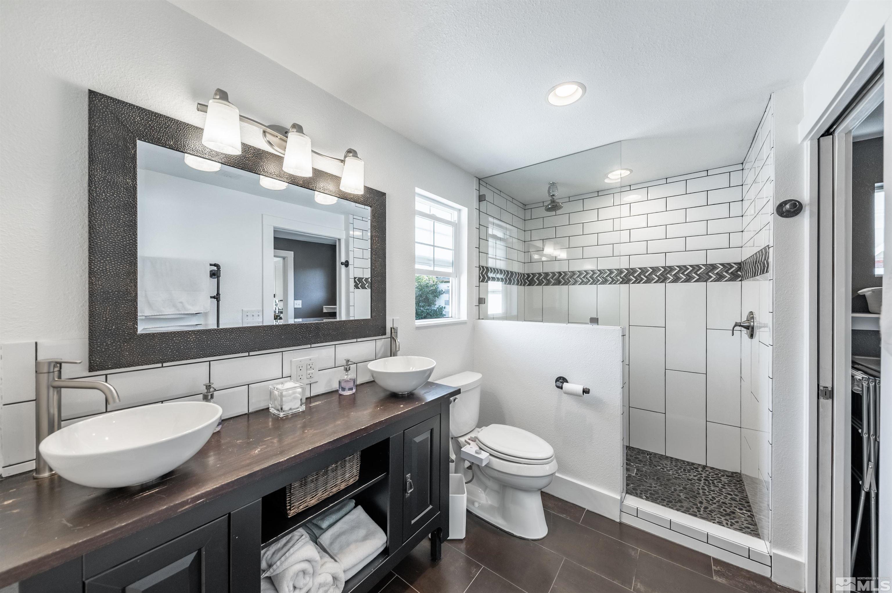 3901 Warren Way Reno, NV 89509 - Photo 20 of 40 a bathroom with a granite countertop sink toilet a mirror a vanity and shower