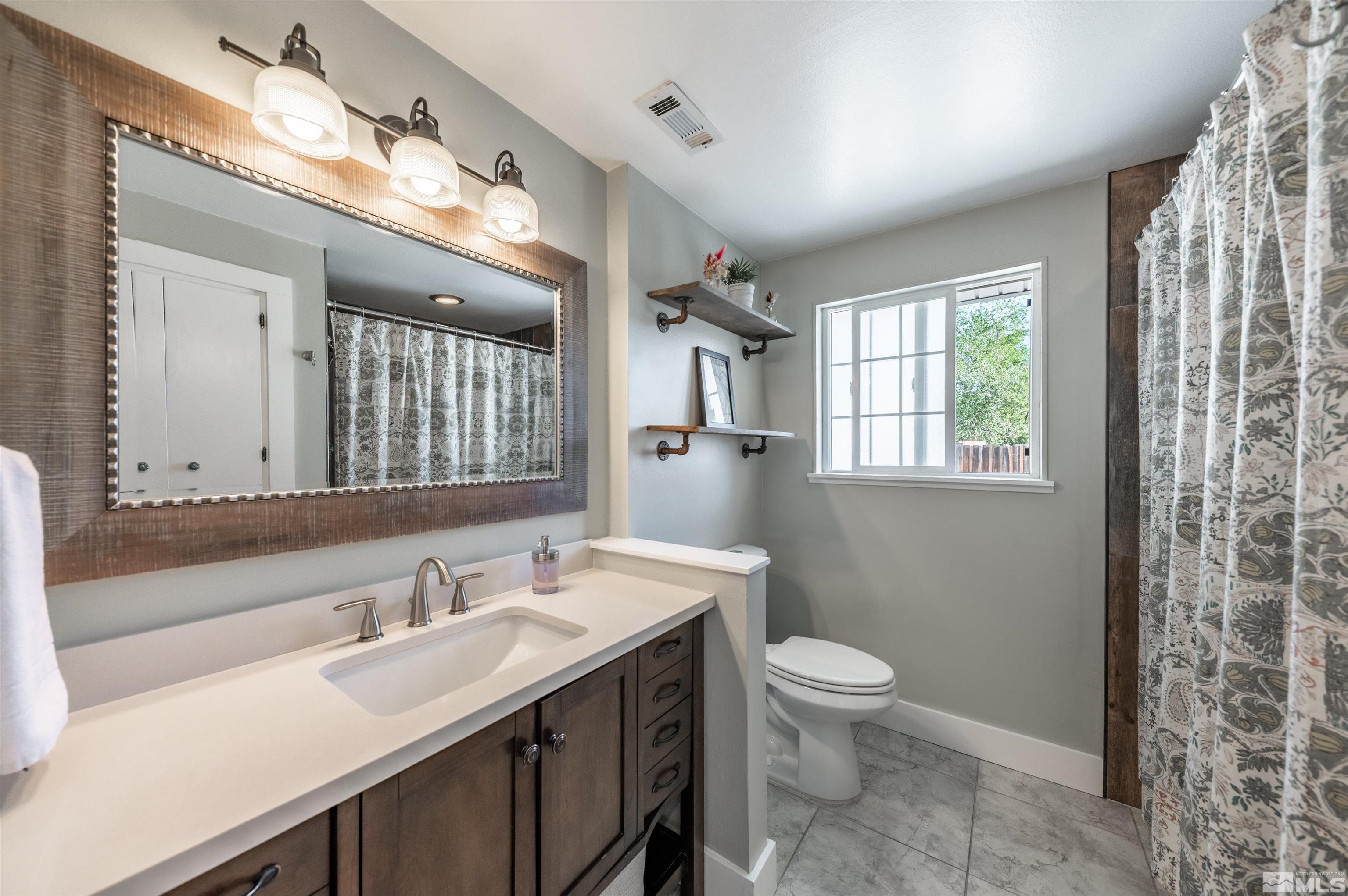 3901 Warren Way Reno, NV 89509 - Photo 23 of 40 a bathroom with a sink a toilet and a large mirror