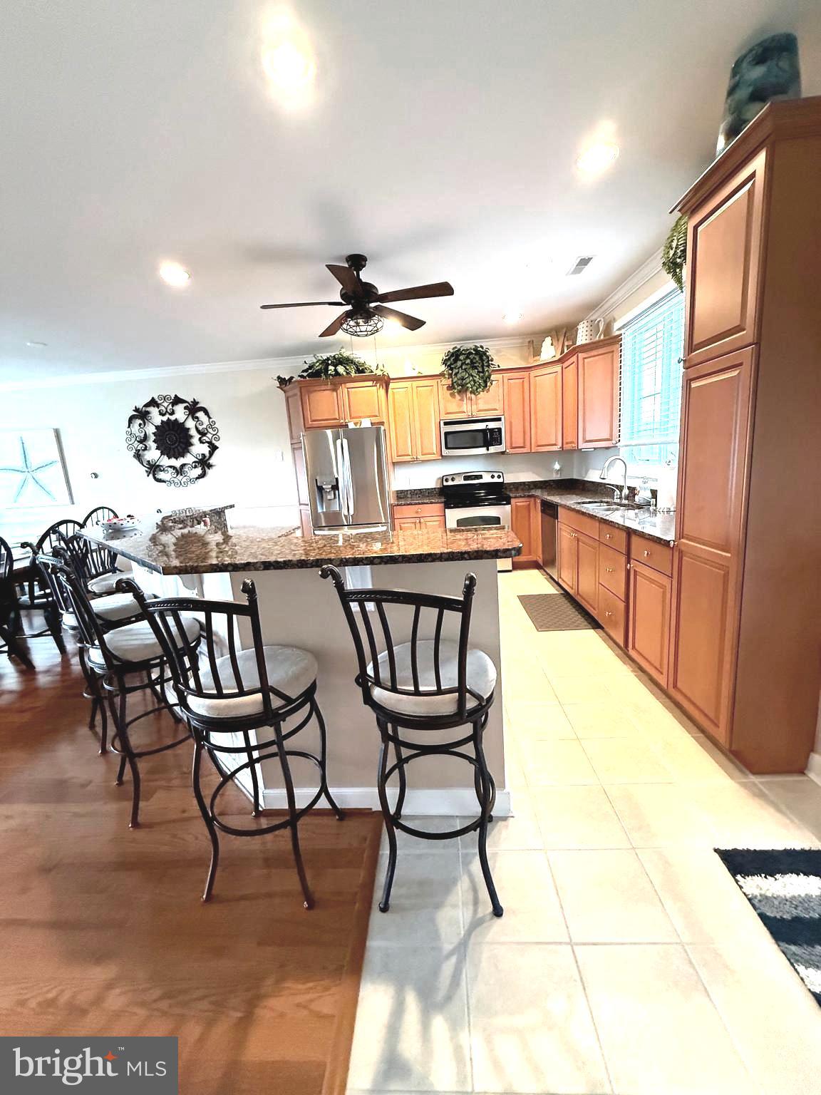 9823 Golf Course Road, Unit 20 Ocean City, MD 21842 - Photo 33 of 61 a kitchen with stainless steel appliances kitchen island granite countertop a table chairs and a refrigerator