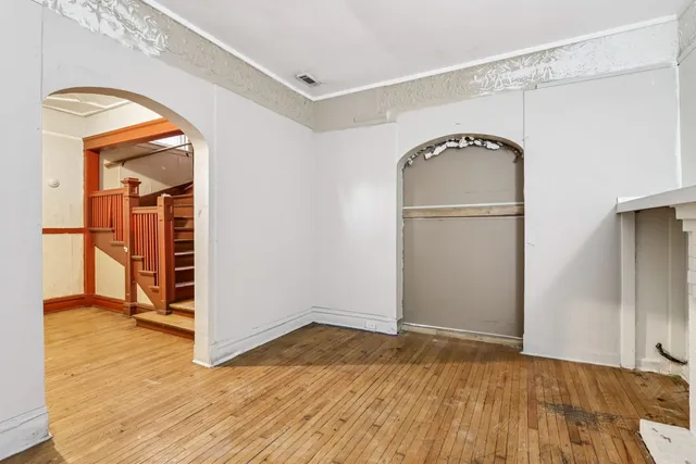a view of empty room with wooden floor and fan