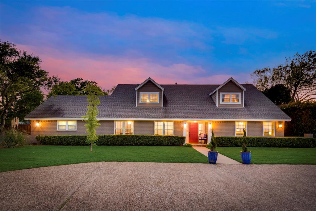 a view of a brick house with a big yard and large trees