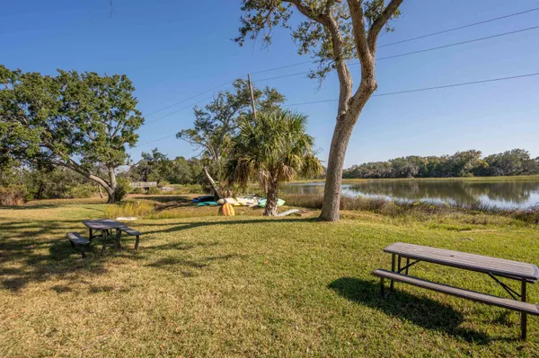 a view of a lake with lawn chairs under an umbrella
