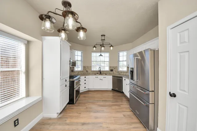 a large kitchen with a chandelier and stainless steel appliances