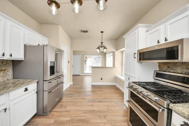 a kitchen with stainless steel appliances and wooden floor