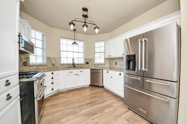 a kitchen with white cabinets stainless steel appliances and window