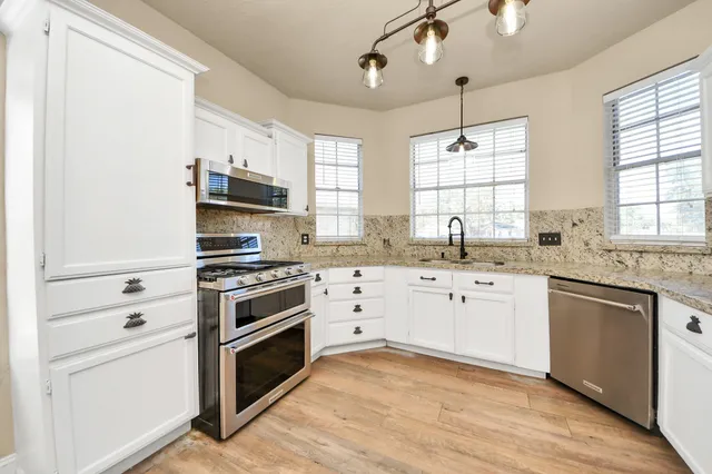 a kitchen with cabinets stainless steel appliances a sink and a window