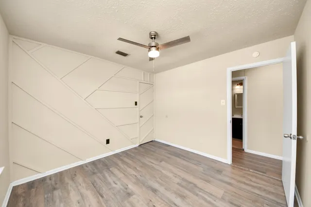 an empty room with wooden floor and ceiling fan