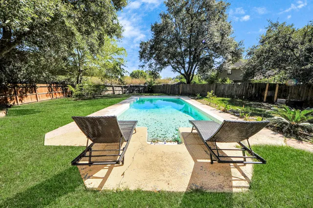 a view of swimming pool with lawn chairs and plants