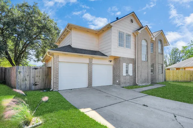 a view of a house with a yard and large tree
