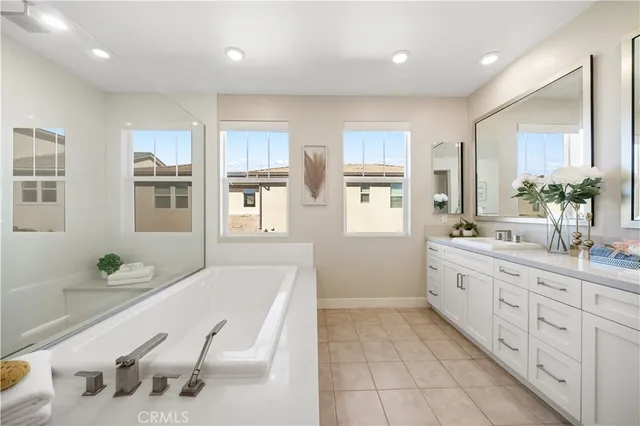a spacious bathroom with a granite countertop double vanity sink a mirror and a bathtub