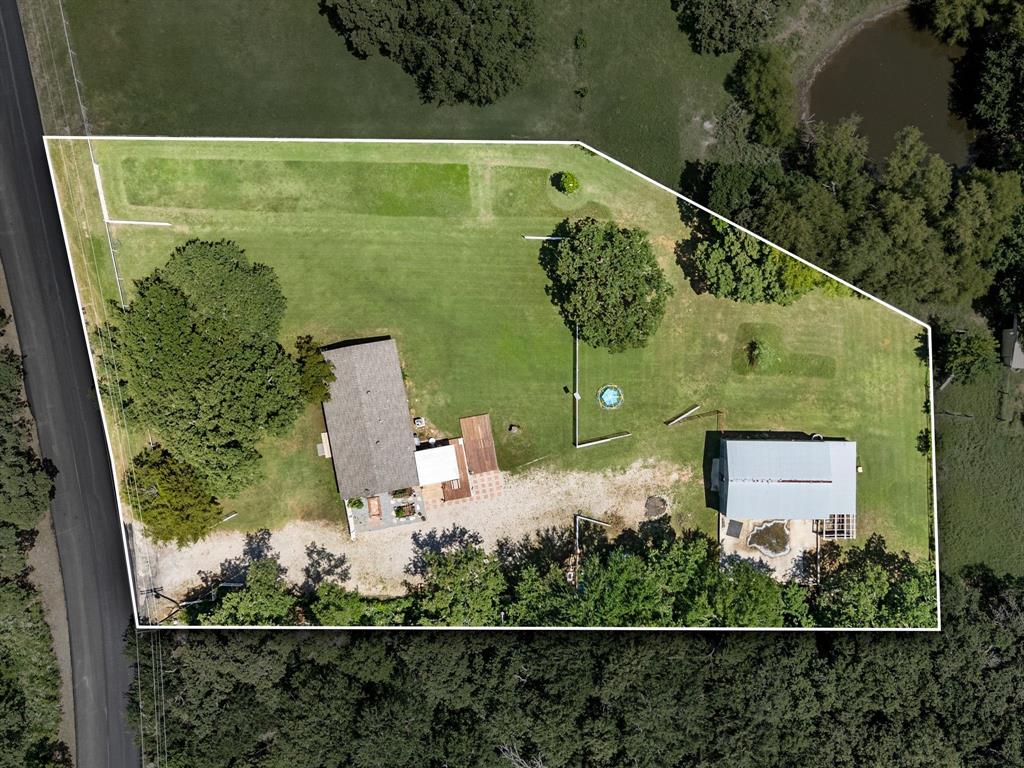 3900 Moseley Road Cross Roads, TX 76227 - Photo 32 of 36 Expansive property featuring a main residence with a gabled roof, an accessory building with a metal roof, and a large gravel driveway