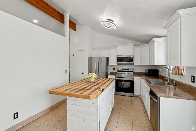 3689 Lasso Loop Circle Magna, UT 84044 - Photo 6 of 26 Kitchen featuring a wood-finish island, white cabinetry, stainless steel appliances, and a vaulted ceiling with exposed beams