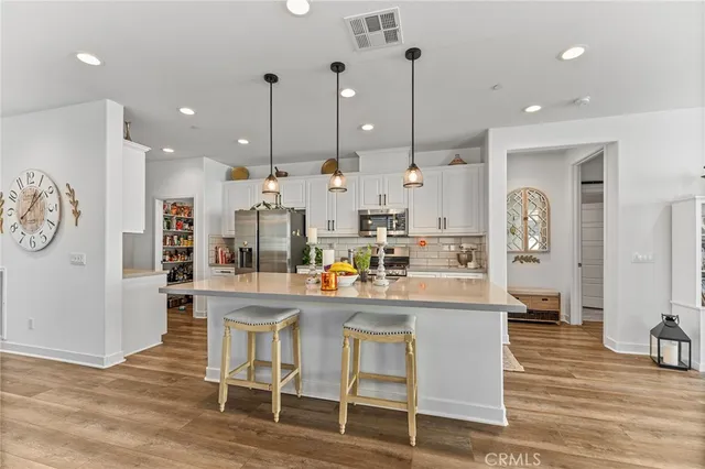 a kitchen with stainless steel appliances kitchen island granite countertop a table chairs and a refrigerator