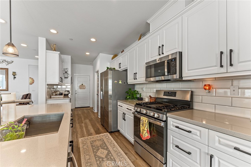 1656 Spring Run Lane Beaumont, CA 92223 - Photo 18 of 40 a kitchen with stainless steel appliances a stove a refrigerator a sink a stove top oven a counter space and cabinets