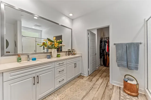a spacious bathroom with a double vanity sink a mirror and shower