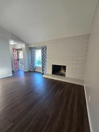 a view of empty room with wooden floor and fireplace