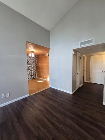 a view of an empty room with wooden floor and windows