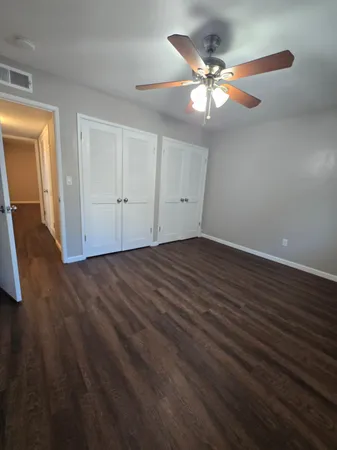 an empty room with wooden floor fan and windows