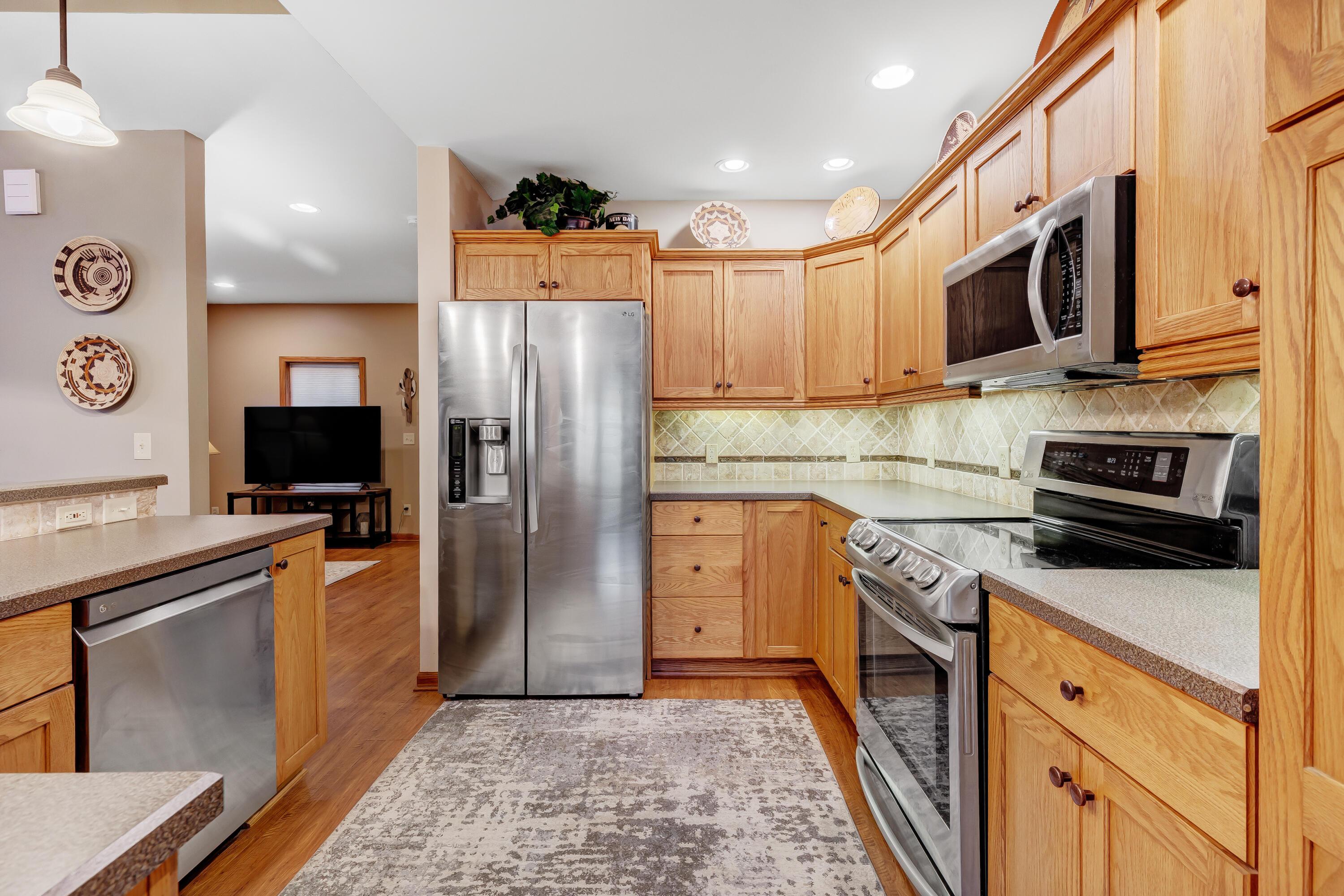 6681 Harlem Road Westerville, OH 43082 - Photo 17 of 78 • Laminate flooring • Tan painted walls • Pendant lighting • Laminate countertops with bevelled edge • Breakfast bar ledge • New LG® refrigerator ~ 2019 • New LG® microwave ~ 2019 • New LG® electric range ~ 2019 • New LG® dishwasher ~ 2019 • Framed cabinets • Wall pantry • Can lighting • Double bowl, stainless steel sink with sprayer • Tumbled marble backsplash