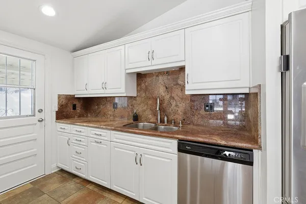 a kitchen with granite countertop white cabinets and stainless steel appliances