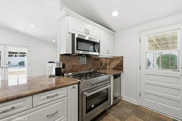 a kitchen with granite countertop a stove a microwave a sink and cabinets