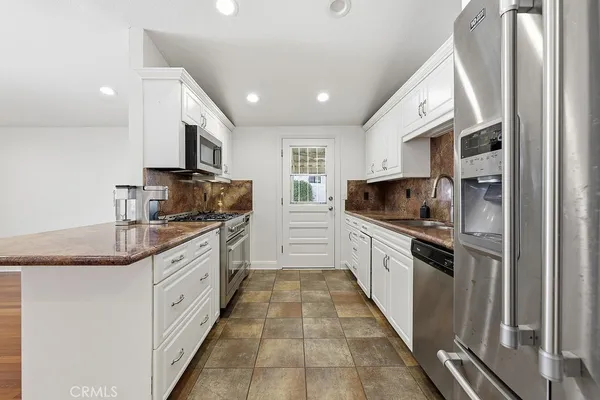 a large kitchen with stainless steel appliances kitchen island granite countertop a sink and cabinets