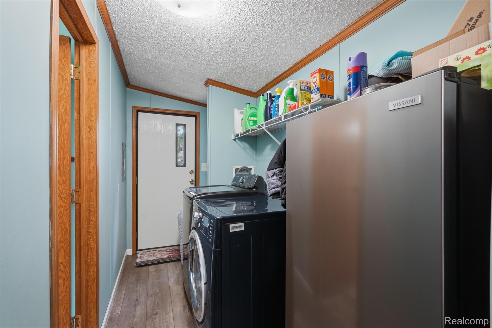 4634 Butternut Street Clarkston, MI 48348 - Photo 21 of 28 Laundry area featuring wood-finish flooring, light blue walls with wood trim, and a built-in wire shelving unit