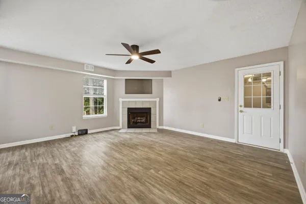 a view of an empty room with wooden floor fireplace and a window
