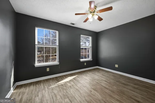 an empty room with windows and ceiling fan