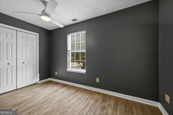 an empty room with wooden floor cabinet and windows