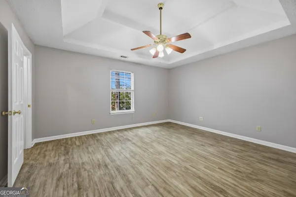 an empty room with wooden floor window and ceiling fan