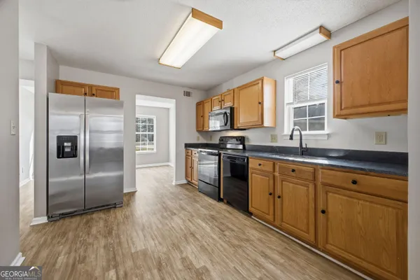 a kitchen with stainless steel appliances granite countertop a refrigerator a sink dishwasher a stove with wooden cabinets and floor