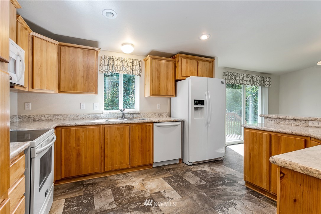 7592 Woodland Road Ferndale, WA 98248 - Photo 12 of 38 a kitchen with granite countertop a refrigerator and a stove top oven