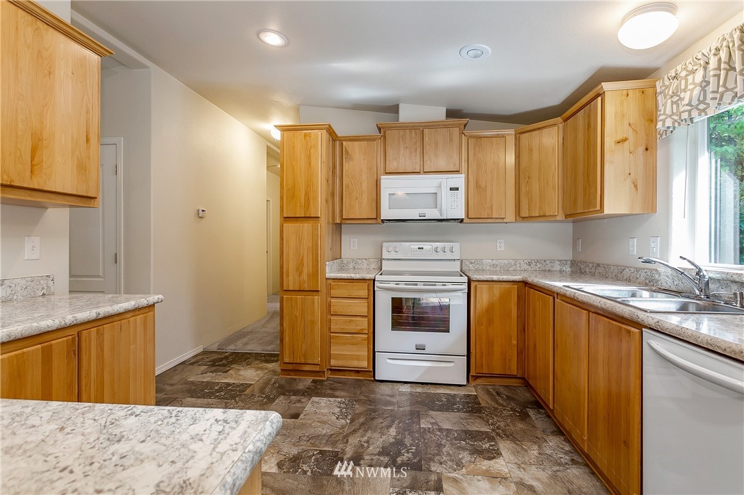 7592 Woodland Road Ferndale, WA 98248 - Photo 10 of 38 a kitchen with stainless steel appliances granite countertop a sink stove and refrigerator