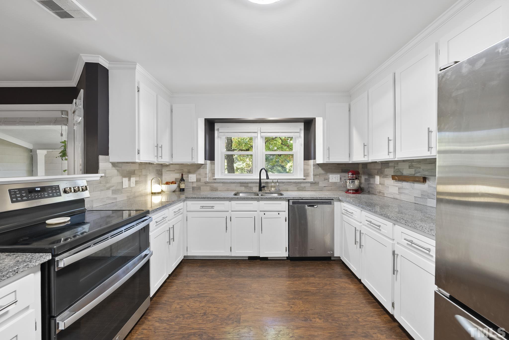 7516 Ray Road Raleigh, NC 27613 - Photo 3 of 23 a large white kitchen with stainless steel appliances granite countertop a stove a sink and a white cabinets
