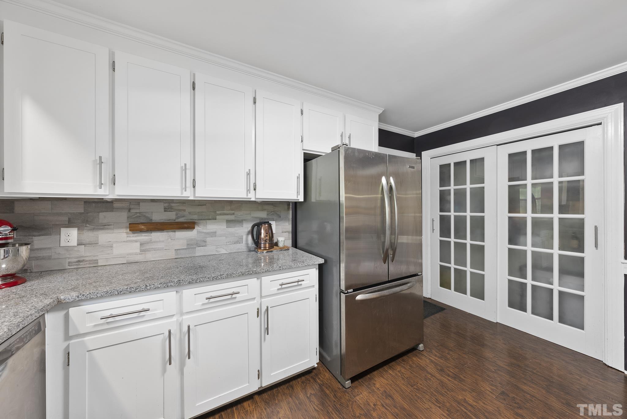 7516 Ray Road Raleigh, NC 27613 - Photo 7 of 23 a kitchen with stainless steel appliances granite countertop a refrigerator a sink a stove and white cabinets with wooden floor