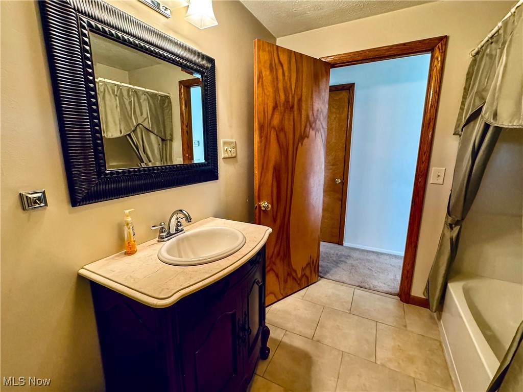 304 Stone Road Belpre, OH 45714 - Photo 11 of 34 Bathroom featuring tile patterned flooring, vanity, shower / bath combination with curtain, and a textured ceiling