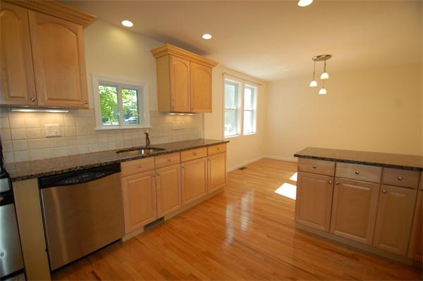15 Woodland Road Wellesley, MA 02481 - Photo 3 of 5 a kitchen with granite countertop a stove a sink a refrigerator and white cabinets with wooden floor
