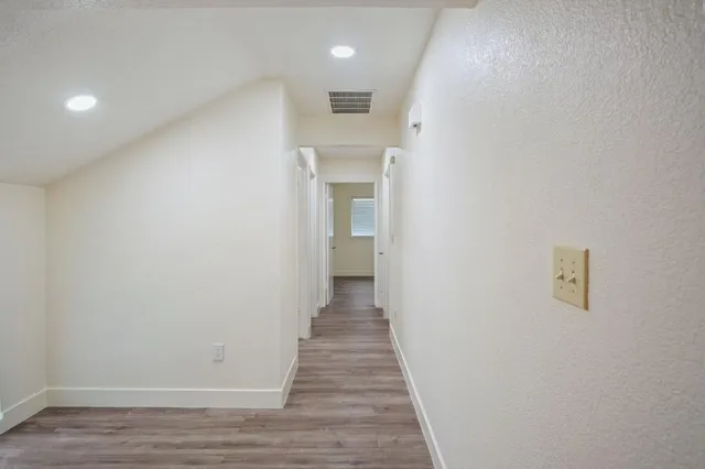 a view of a hallway with wooden floor and a refrigerator