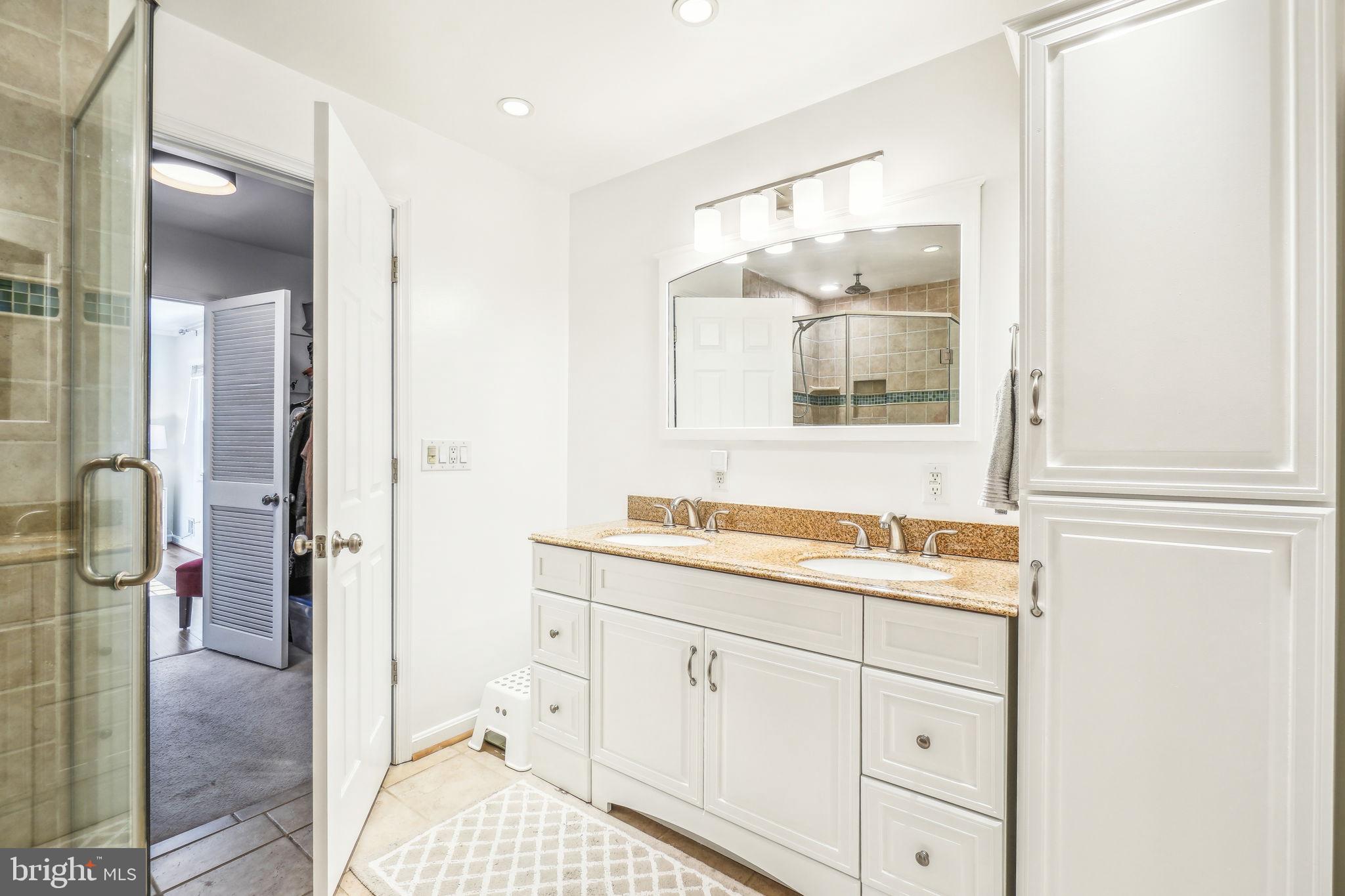 8248 Carrleigh Parkway Springfield, VA 22152 - Photo 16 of 45 a en suite bathroom with a sink a mirror and a shower