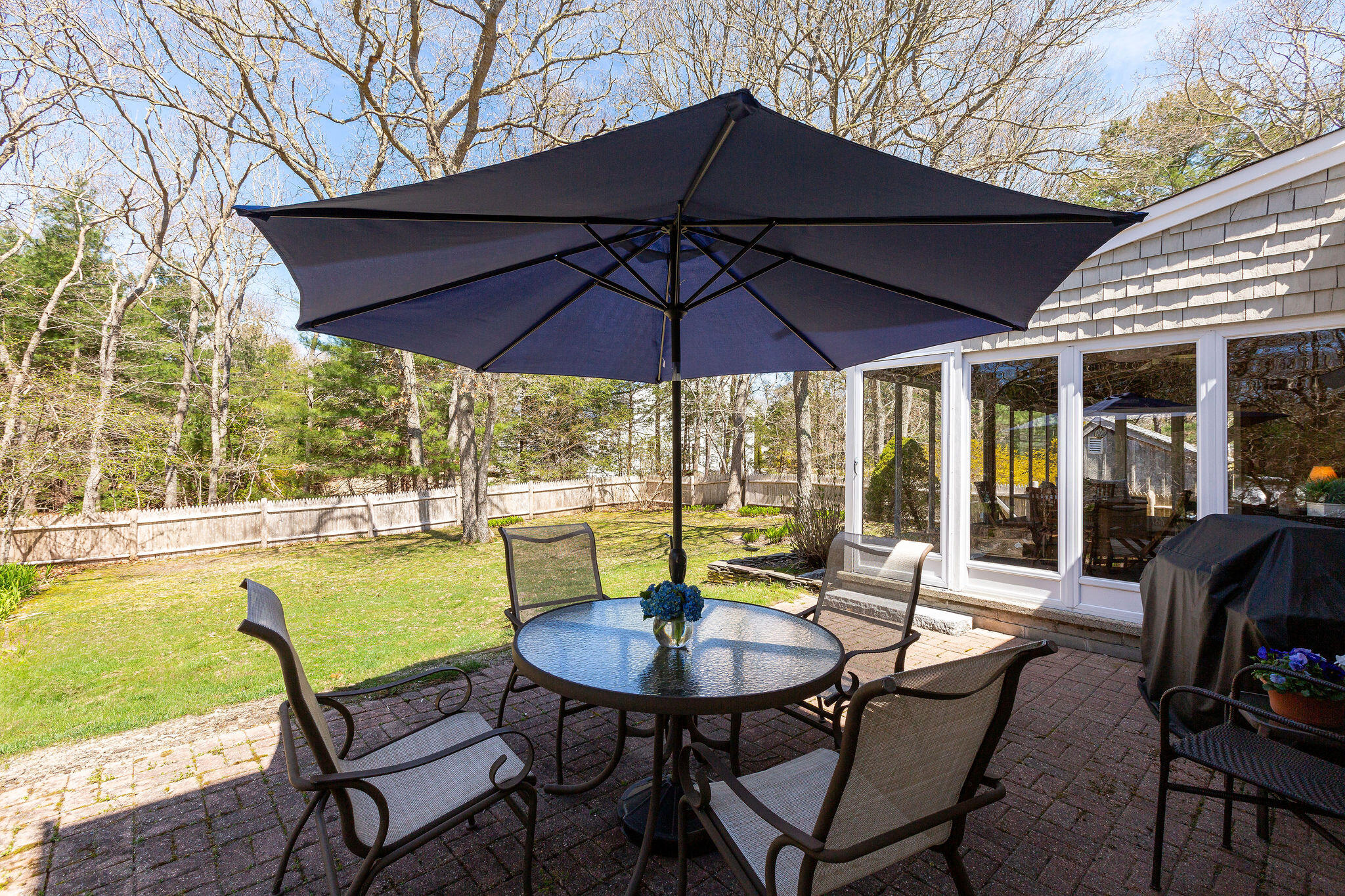 89 Screecham Way Cotuit, MA 02635 - Photo 46 of 50 a patio with a table and chairs under an umbrella
