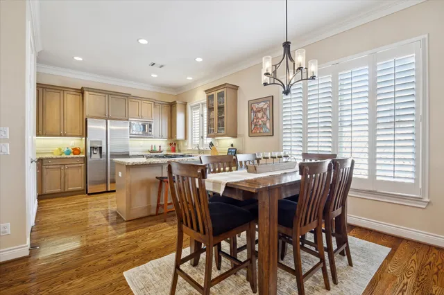 a dining room with stainless steel appliances kitchen island granite countertop a dining table chairs and a refrigerator