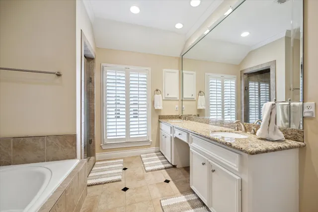 a bathroom with a granite countertop sink and a bathtub