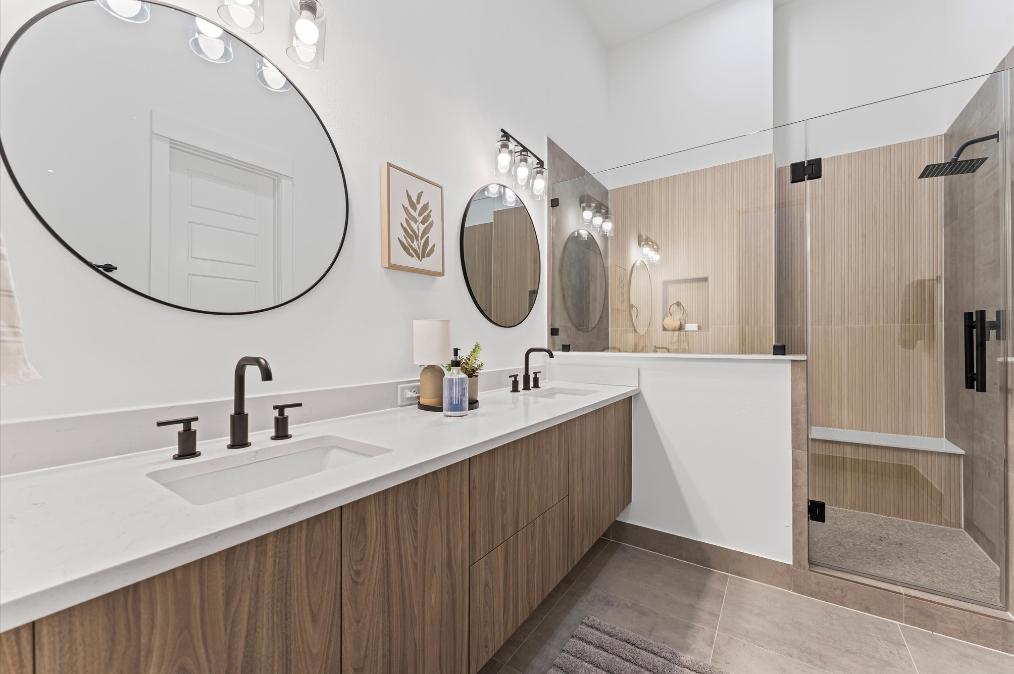 2424 Freeman Street Houston, TX 77009 - Photo 24 of 43 The luxurious primary ensuite features sleek modern finishes, a glass-enclosed shower with stylish tile, and a double-sink vanity topped with quartz countertops, complemented by two contemporary mirrors and lighting fixtures, creating a bright, elegant, and functional retreat.
